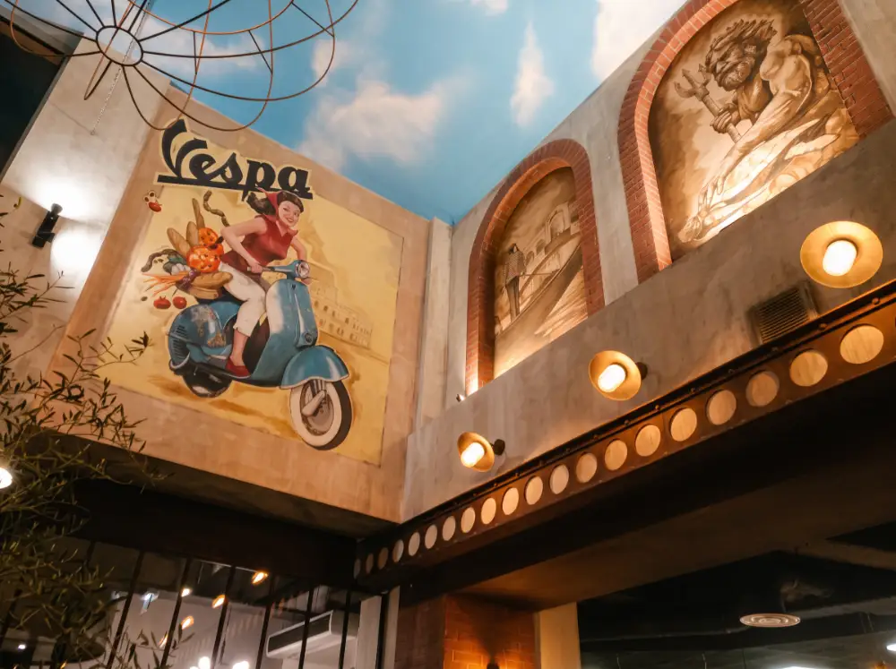 Le plafond peint en ciel bleu, la fresque Vespa et les fresques sépia dans leurs arches de brique
