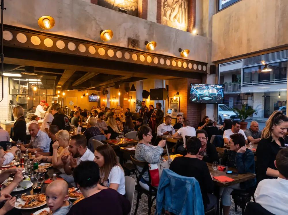 Une soirée animée : tables pleines, pizzas à partager et musiciens au fond de la salle
